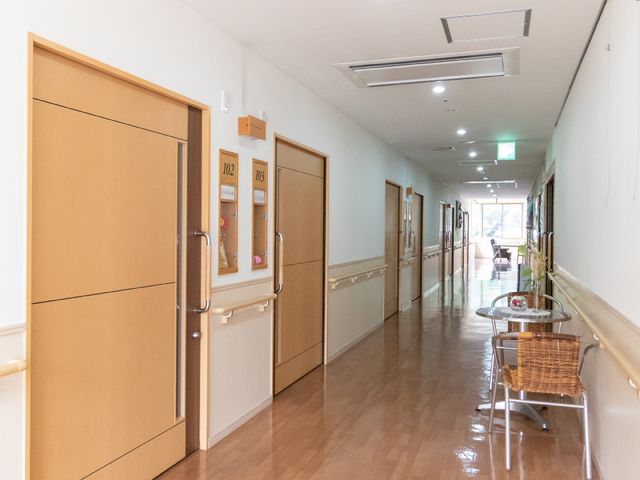 清潔な施設の廊下 廊下 清潔感のある廊下は日差しが差し込み、心地よい雰囲気です。キャスター付き椅子も用意され、休憩にも適しています。