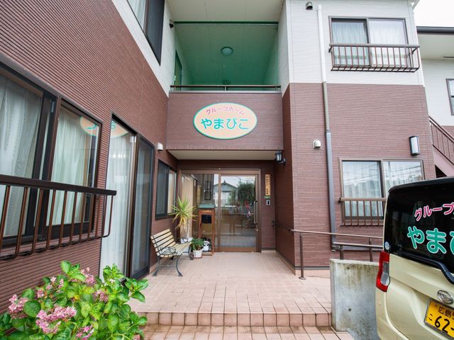 温かみのあるエントランス 玄関 広々とした入り口は、来訪者を暖かく迎え入れる空間です。待合のベンチが設置され、心地よい待ち時間を提供しています。