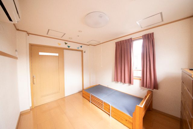 ゆったりとした居室 スライド式ドア 広々とした居室で、窓から光が差し込み明るく快適な空間が広がっています。ベッド周りには手すりが備わり、安心してお過ごしいただけます。