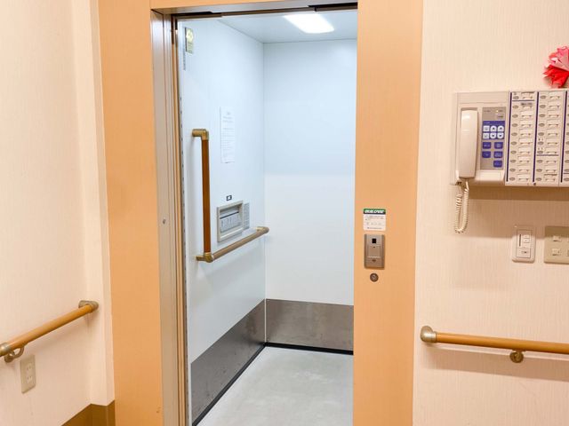 明るいエレベーター エレベーター 壁には手すりがついていて、安全に配慮されたエレベーターです。飾り付けが温かみを感じさせます。