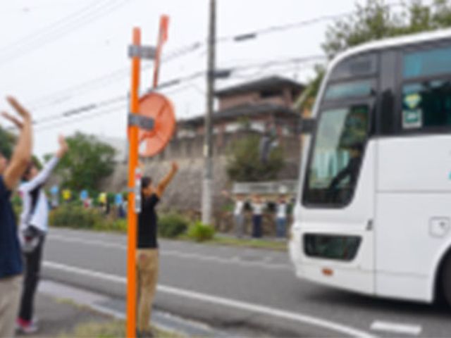 バス見送りの様子 エントランス スタッフがお客様を見送りしている現場です。笑顔で手を振りながら、温かい雰囲気を感じられます。