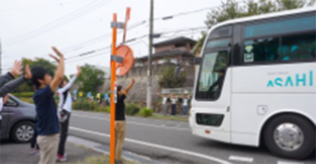 バス見送りの様子 エントランス スタッフがお客様を見送りしている現場です。笑顔で手を振りながら、温かい雰囲気を感じられます。