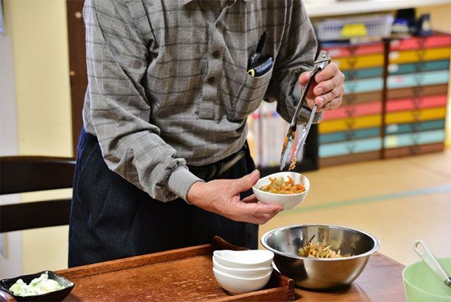 食事準備中の様子 食堂 食事の準備を楽しむ光景。スタッフと協力し、和やかな雰囲気の中で配膳作業を行っています。