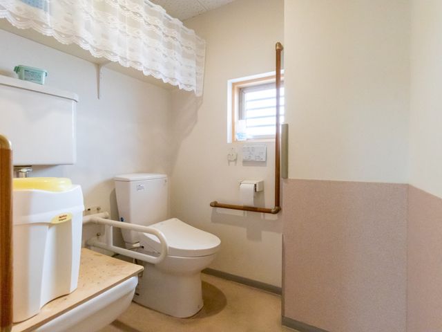 バリアフリーの洋式トイレ トイレ 手すり付きで安心した使い心地の洋式トイレです。日差しが入る窓からは清潔感が感じられ、リラックスできる空間になっています。