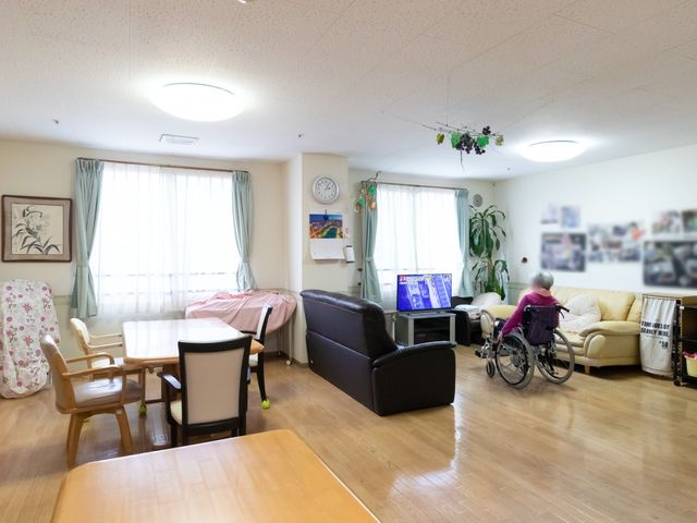居室の広々とした空間 リビングダイニング ゆとりのある居室で、テレビ視聴やくつろぎの時間を過ごされる方の様子が伺えます。明るく暖かみのある雰囲気が、安らぎのひとときを提供しています。