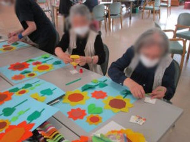 創作活動を楽しむテーブル 多目的室 広々とした多目的室では、利用者が楽しく創作活動に取り組んでいます。色とりどりの作品が作られています。