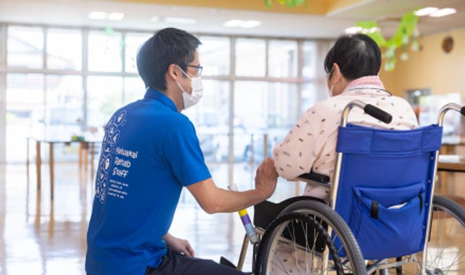 車椅子の高齢者と職員が会話するラウンジ