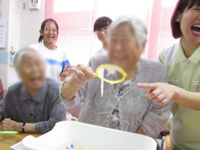 笑顔が溢れる室内風景 多目的室 明るい室内で、スタッフと利用者が楽しく過ごしている様子が伝わります。笑顔が絶えない環境です。