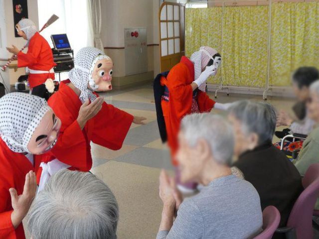 演芸を楽しむ様子 会場 多目的室 演芸が行われており、利用者の方々が和やかに楽しんでいる光景が広がっています。リラックスできる雰囲気です。