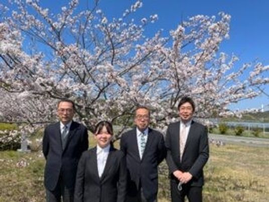 桜の下に立つ4人の外観  