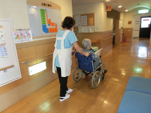 車椅子の介助風景廊下 廊下   介護士が車椅子の方をサポートしています。温かい対応が可能な環境で働けます。