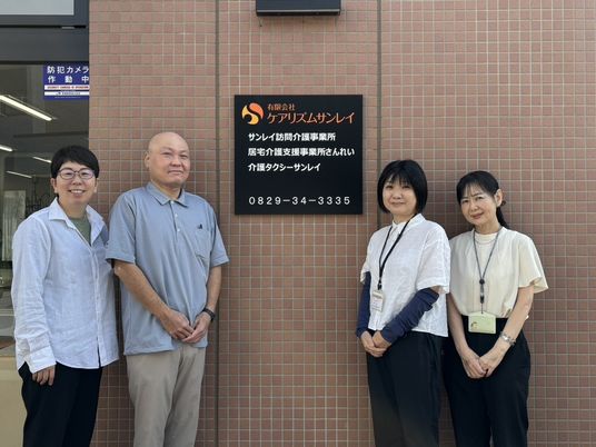 スタッフ4人が看板前に立つ外観  