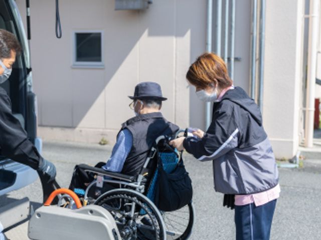 介護サポートの様子 スタッフイメージ 車椅子の方をサポートしながら、安全に移動をお手伝いするスタッフの様子です。
