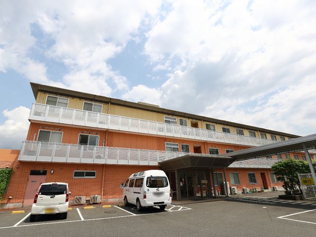 オレンジ色の建物外観 施設外観 明るい色合いの建物が迎える、快適な新天地です。車いすでも安心のスロープが備わっています。