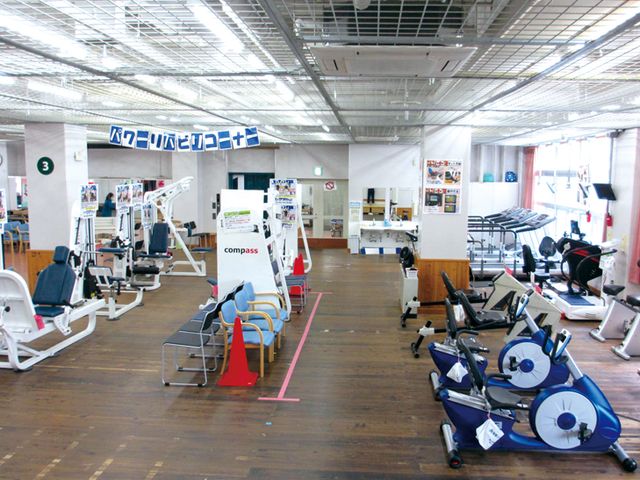 運動器具が並ぶ室内空間 ジム 広々としたジムで、様々な器具を使って快適にトレーニングを行うことができます。明るい照明が特徴的です。