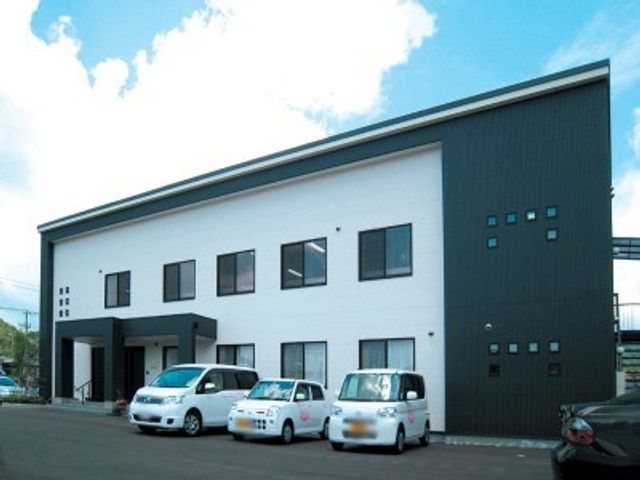 車が並ぶ建物外観 外観 モダンな外観の建物は、快適な就業環境を提供します。駐車スペースも完備されています。