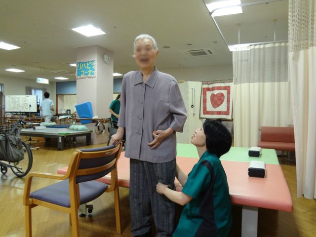トレーニング中の部屋 機能訓練室 自然光が差し込む明るい空間で、専門スタッフがサポートする機能訓練の様子です。利用者に寄り添ったサポートが魅力です。