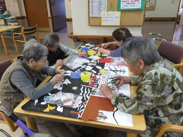 手作業に集中する人々の様子 ラウンジ ラウンジでは、入居者の皆さんが手作業を通じて充実した時間を過ごされています。暖かみのある空間で、コミュニケーションも活発です。