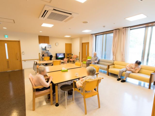 共有スペースの様子 リビング ゆったりとした座席配置のラウンジで、ご利用者がくつろいでいます。柔らかな光が差し込む窓際では、安らぎのひとときを提供しています。