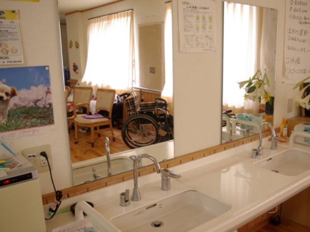 車椅子が置かれた洗面台 洗面台 明るい空間には車椅子も設置でき、利用者が快適に過ごせるように工夫されています。