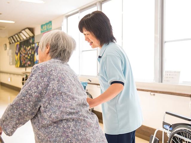 明るい廊下の様子 廊下 窓からの自然光が差し込む明るい廊下です。スタッフが利用者を丁寧にサポートしています。