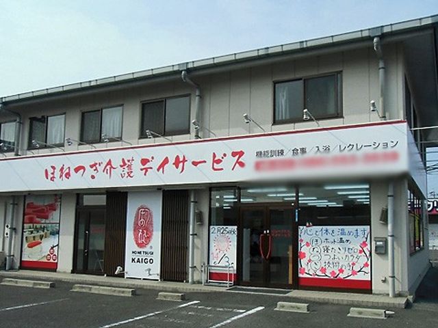 看板が目立つ建物の外観 看板 明るい看板が印象的なこの建物はアクセスしやすい場所に位置し、広々とした駐車場を完備しています。