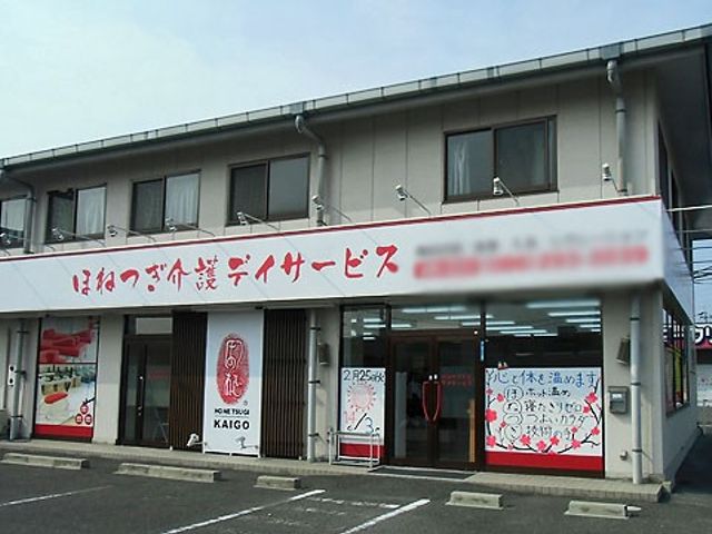 明るい出入口の看板 看板 広々とした駐車スペースと明るい入口を備えた施設です。温かいおもてなしを感じられます。
