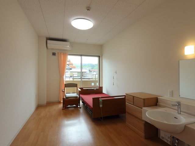 ベッドと洗面台がある居室 居室 自然光が差し込む広々とした空間です。快適に過ごせる落ち着きのある設計です。