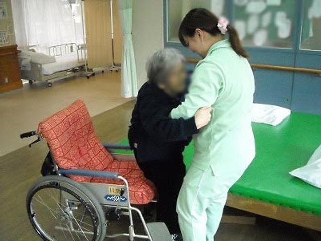 職員が入居者をケアする光景 機能訓練室 職員が、利用者への丁寧なケアを行っています。温かいサービスに触れられる環境です。