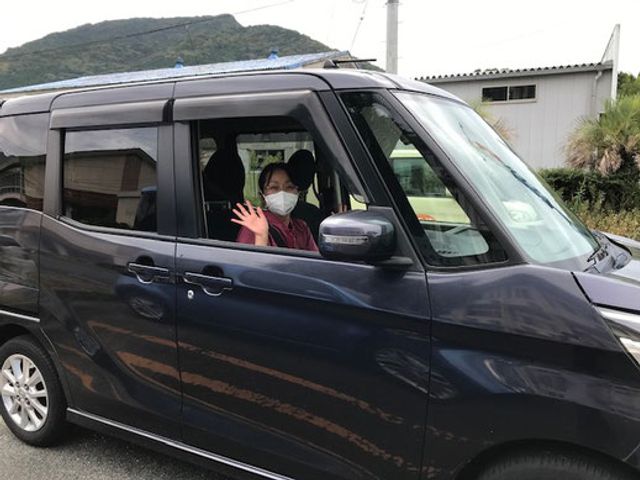 車に乗るスタッフの様子 スタッフイメージ 車内から笑顔で手を振る様子は、温かさと親しみやすさを感じさせます。