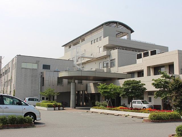 白い外壁の建物外観 外観 緑に囲まれた落ち着いた雰囲気の建物です。ゆったりとした駐車スペースも備わっています。
