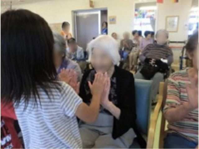 活気ある食堂の様子 イベント 明るい食堂で利用者が手を合わせている光景。周りには他の利用者の姿もあり、和やかな雰囲気が伝わります。