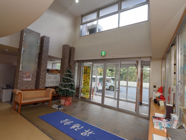 明るいエントランス空間 玄関 天井が高く開放的な受付エリアです。クリスマスツリーが設置され、季節感のある温かみのある雰囲気を楽しめます。