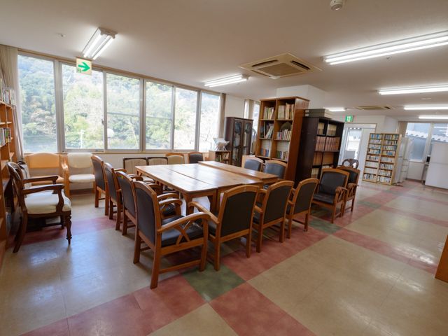 明るい共有リビングスペース デイサービス 窓から自然光がたっぷり差し込む快適な読書空間です。豊富な蔵書とゆったりとした椅子が、休息のひとときを提供しています。