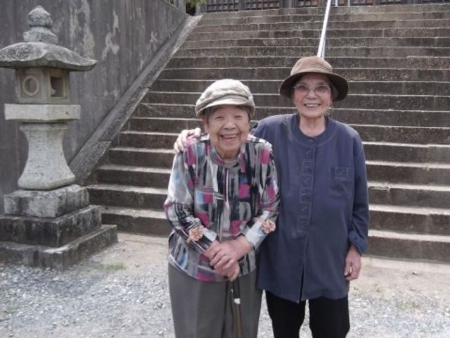 笑顔の高齢者二人 入居者様 日々の散歩やおしゃべりに最適な屋外環境です。新しい仲間と共にゆったりとした時間を過ごしませんか。
