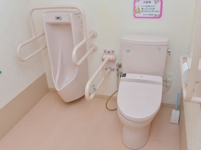 バリアフリー構造のトイレ トイレ 手すり付きのトイレと、壁には使用方法の説明もあり、安全に快適にご使用いただけます。サポートが必要な方にも配慮された設計です。