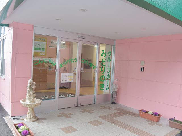 ピンクの壁のエントランス 入口 温かみのあるピンク色の壁に囲まれたエントランスです。訪れる方々をやさしく迎え入れる配色が特徴です。