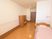 フローリングの床の居室で、壁にはピンク色のラインがある。室内に介護ベッドとドレッサーが置かれている。入り口はスライドドアである。