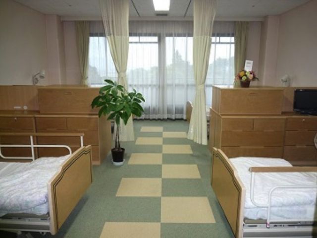 木のベッドがある居室 居室 広々とした居室には、快適な木製ベッドが配置されています。自然光が優しく差し込む空間です。