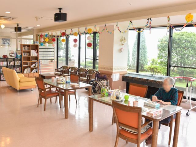 居心地の良いリビング空間 食堂2 広々とした窓と光沢のある床が心地よいラウンジ。利用者がくつろぐ姿が見られます。