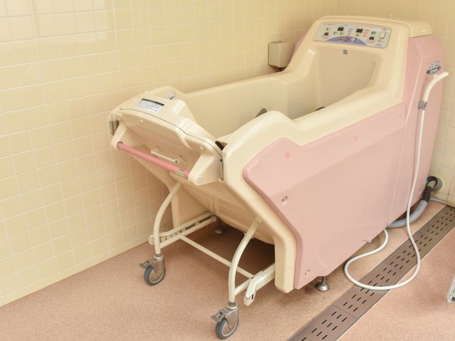 ピンク色の快適浴槽 機械浴槽 ゆったりとしたバリアフリー設計の浴槽があり、安心してご利用いただける環境です。
