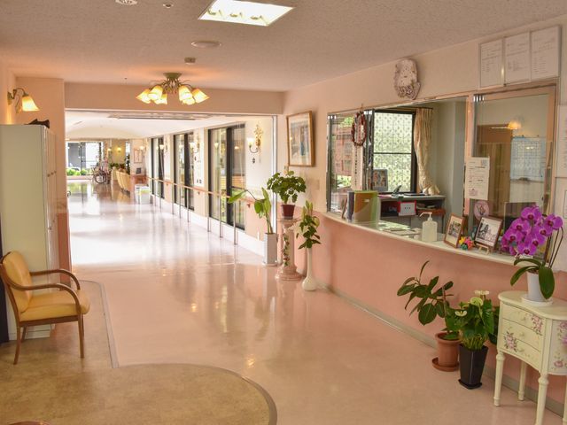 清潔な廊下とフロント エントランス 広々として清潔感のあふれる通路には落ち着きのある照明が優しい雰囲気を醸し出しています。働くスタッフの心地よい対応が感じられる空間です。