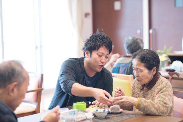 笑顔で食事のサポート 穏やかな食事時間に、スタッフが優しく手助けしています。暖かい対応には、訪れた人も和むでしょう。