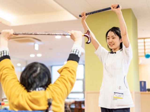 機能訓練を行う様子 機能訓練室 明るく清潔な空間で、スタッフの指導のもと、リハビリテーションに励む様子が伺えます。安心して日々の体力維持を行える環境です。