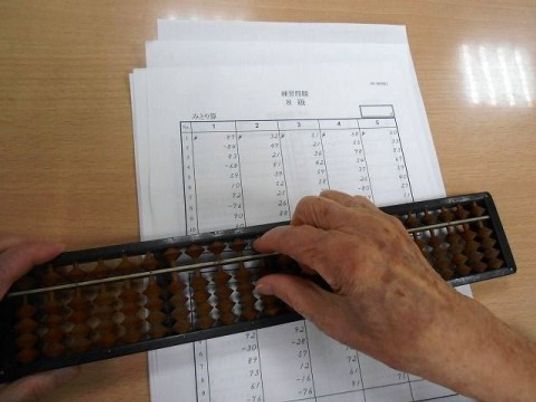 入居者様が解答用紙の上にそろばんを置いて、問題を解いている。解答用紙には数字がたくさん書かれている。