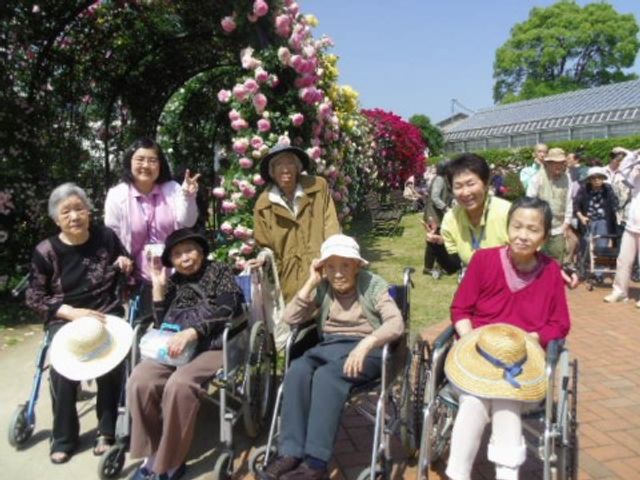 笑顔の集い中庭 外出 中庭では、利用者の方々が心地よい陽気の中、様々な植物に囲まれながら笑顔で交流されています。