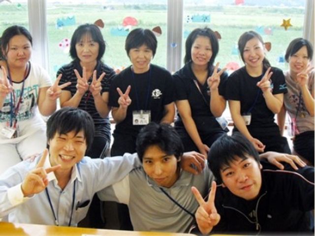 スタッフが笑顔でポーズ スタッフ 和気あいあいとした雰囲気の中、スタッフが楽しそうにポーズをとっています。ここでは、チームワークを大切にして日々の仕事が行われているようです。