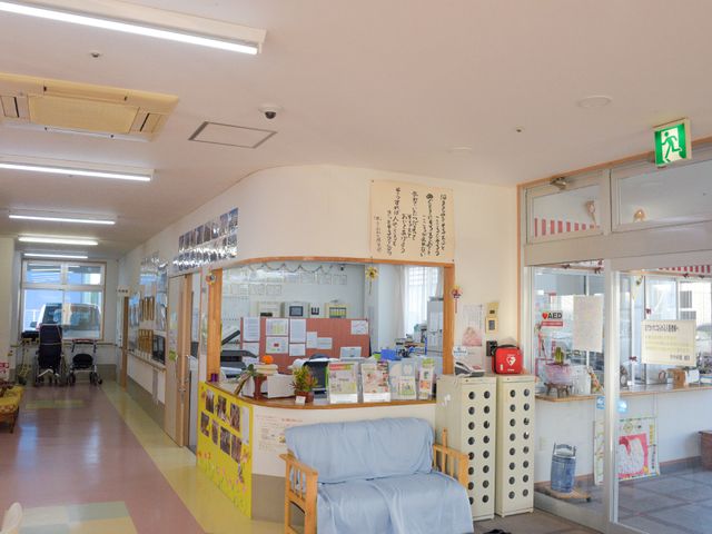 廊下とフロントの様子 玄関 明るく開放的な受付エリアは、広々としており安心感を与える空間です。こちらでご利用者様の日々のサポートが行われています。