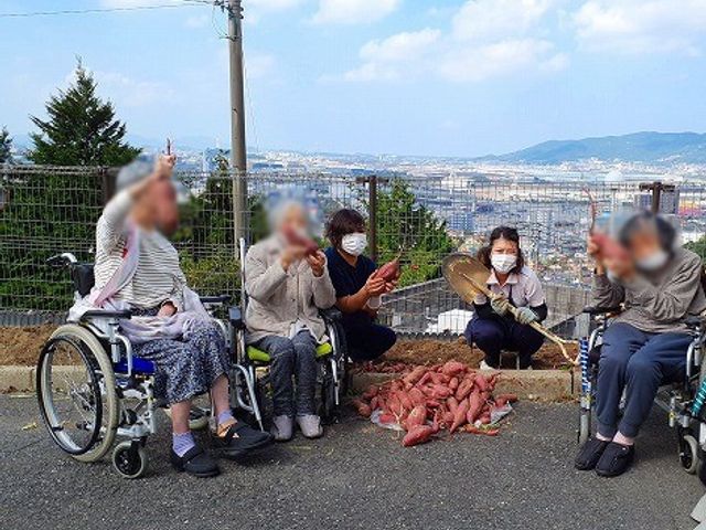 山の見える屋外スペース 中庭 広々とした屋外スペースで、入居者の方々がリラックスした時間を過ごされています。