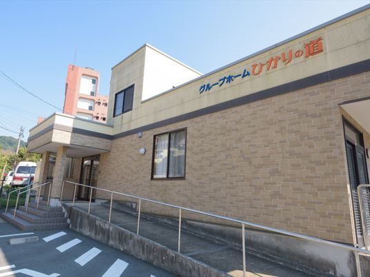施設の外壁には大きく施設名が書かれてている。手すり付きの長いスロープがある。車椅子専用駐車場もある。